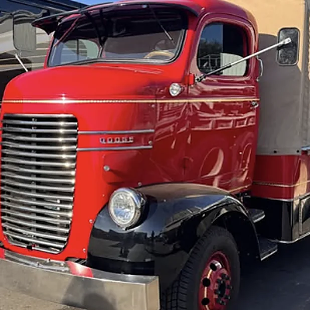 A restored classic red truck with black fenders