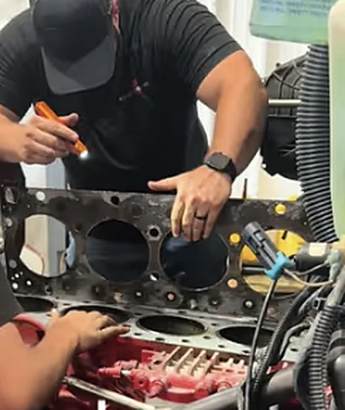 Two NextGen Diesel technicians working on an engine block