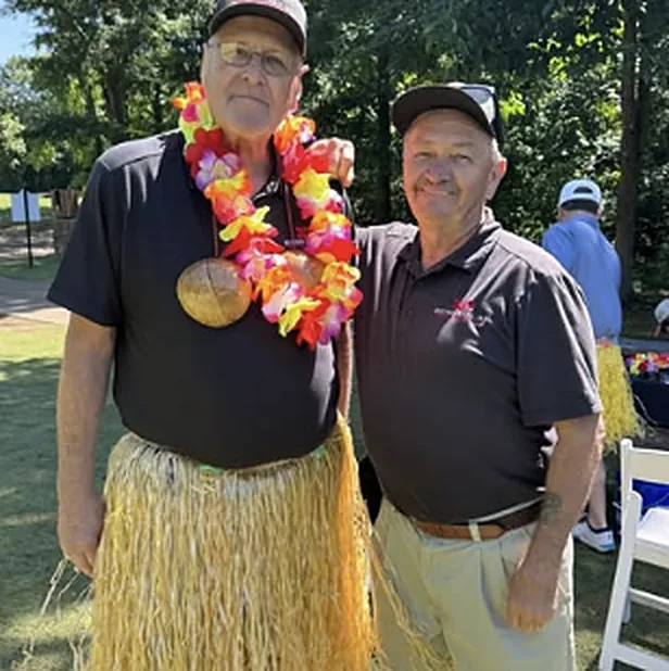 Two men in leis at a community golf event
