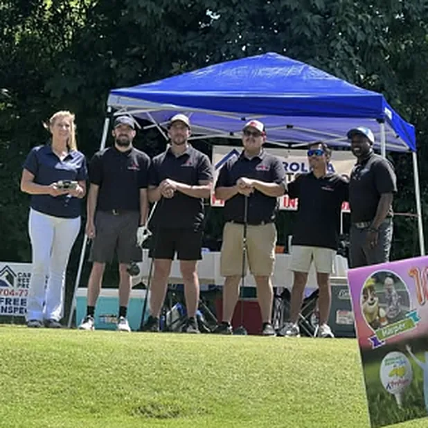 The NextGen Diesel team in matching shirts under a tent at a charity golf event