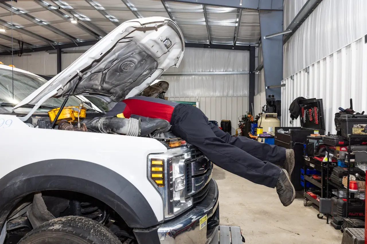 Technician servicing a white diesel pickup in the NextGen Diesel shop