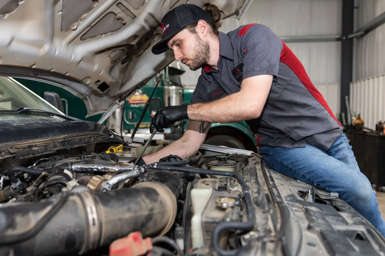 NextGen Diesel technician working under a truck hood