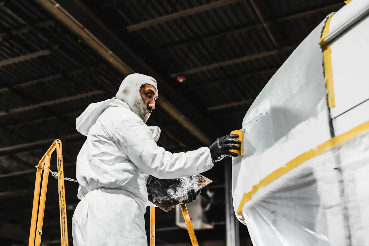 Technician in protective gear repairing a truck body panel